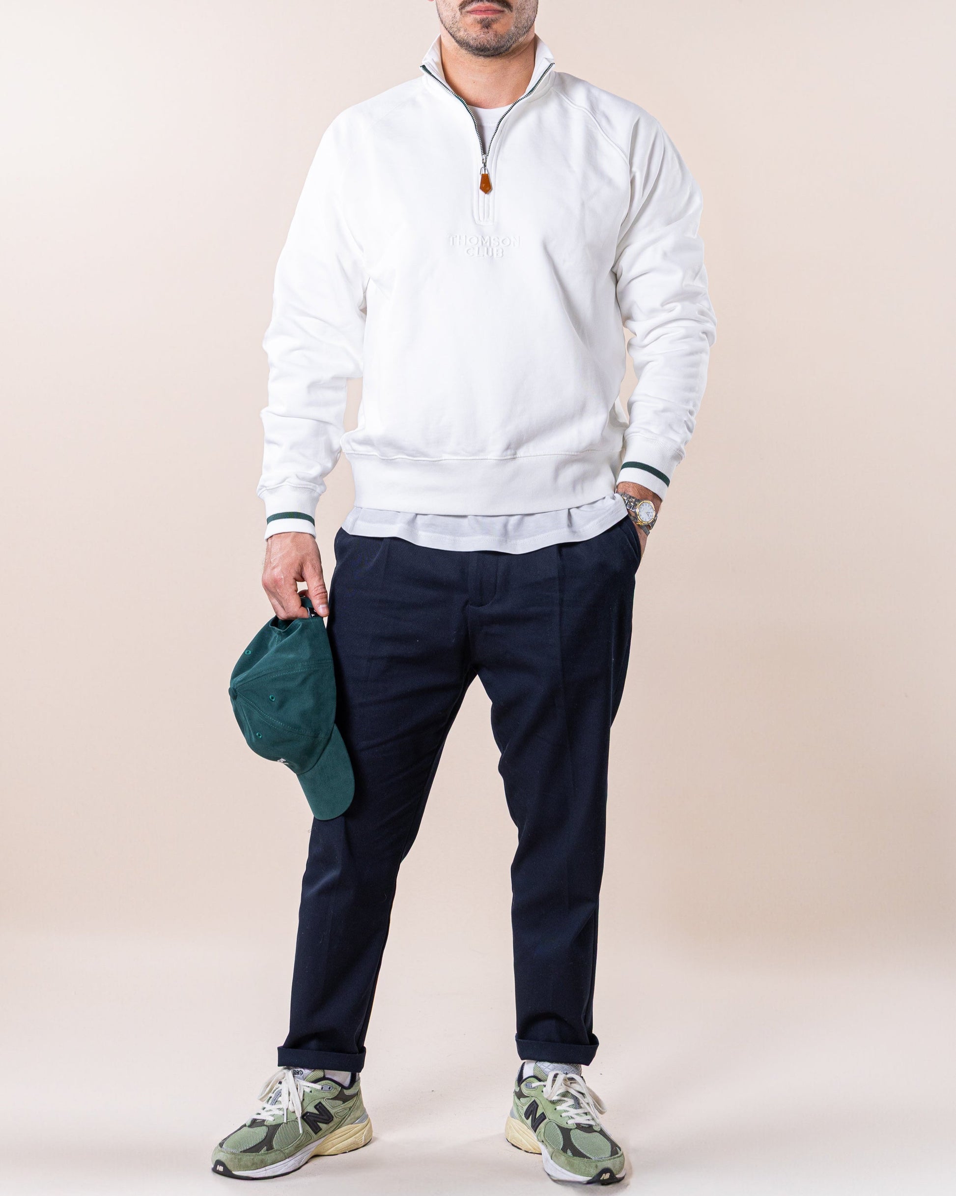 Quarter-zip off-white de homem, feito de 100% algodão orgânico, com felpa premium e corte relaxado. Mangas raglan para maior liberdade de movimento e gola alta com punhos e bainha em rib 1X1 para ajuste confortável. Detalhes como o bordado Thomson Club em relevo e o puxador TC personalizado em couro premium destacam a qualidade da peça. Ideal para um visual descontraído, moderno e sofisticado.