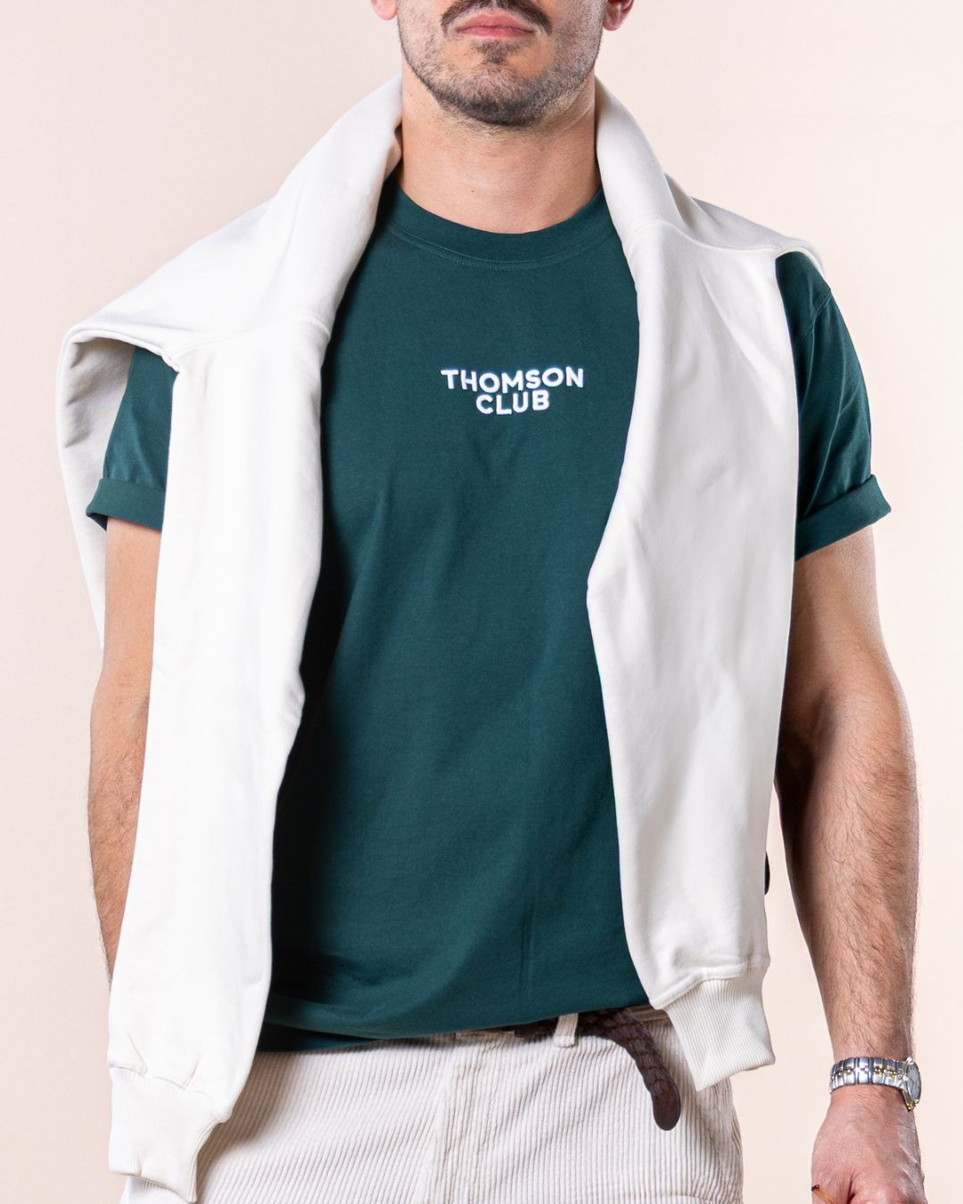 T-shirt verde de homem em algodão orgânico, corte relaxado com gola rib 1X1 e costuras de alta qualidade. Logotipo Thomson Club bordado em relevo e tag metálica nas costas. Visual simples e versátil, ideal para diversas combinações e ocasiões do dia a dia, equilibrando estilo clássico e desportivo.