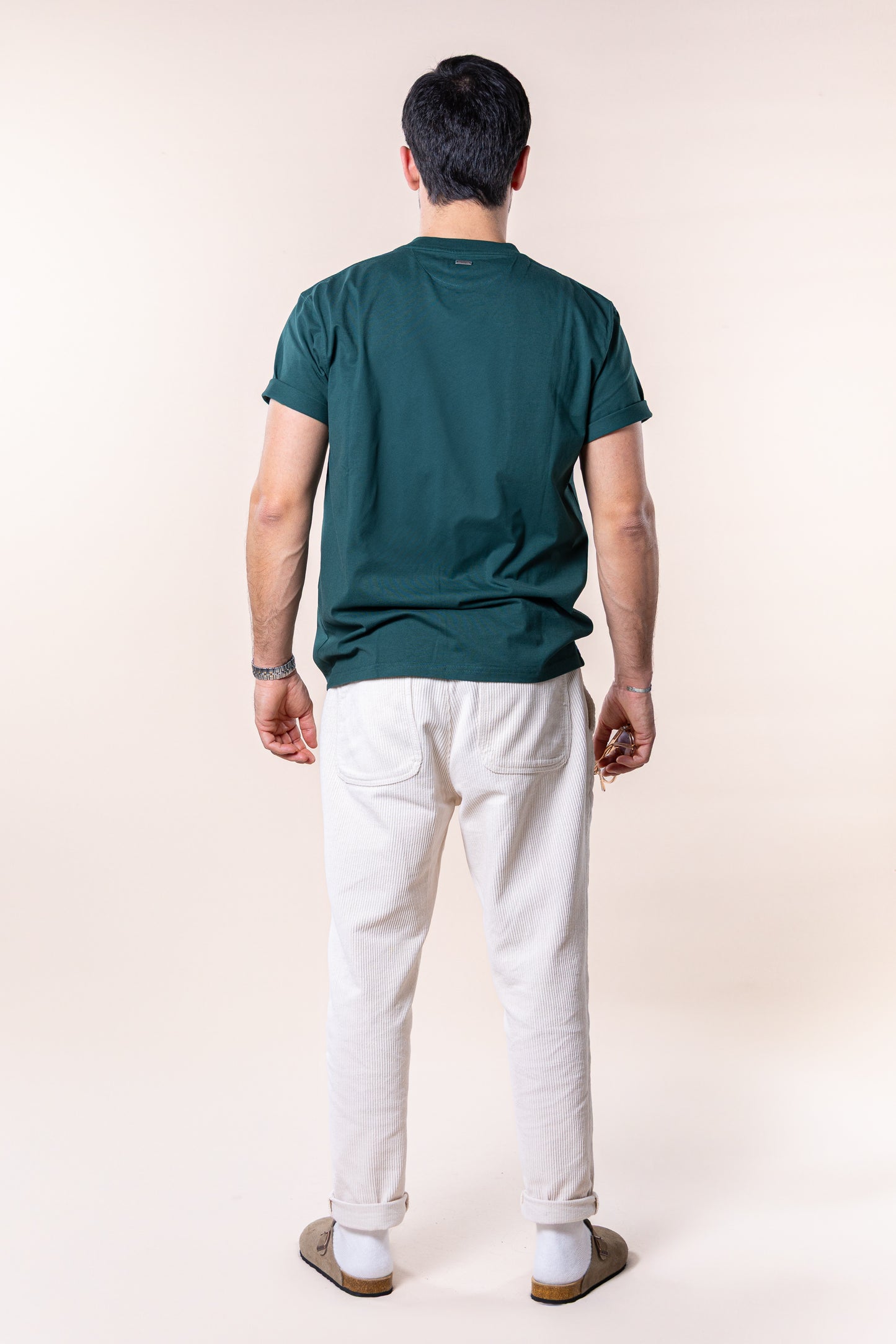 T-shirt verde de homem em algodão orgânico, corte relaxado com gola rib 1X1 e costuras de alta qualidade. Logotipo Thomson Club bordado em relevo e tag metálica nas costas. Visual simples e versátil, ideal para diversas combinações e ocasiões do dia a dia, equilibrando estilo clássico e desportivo.