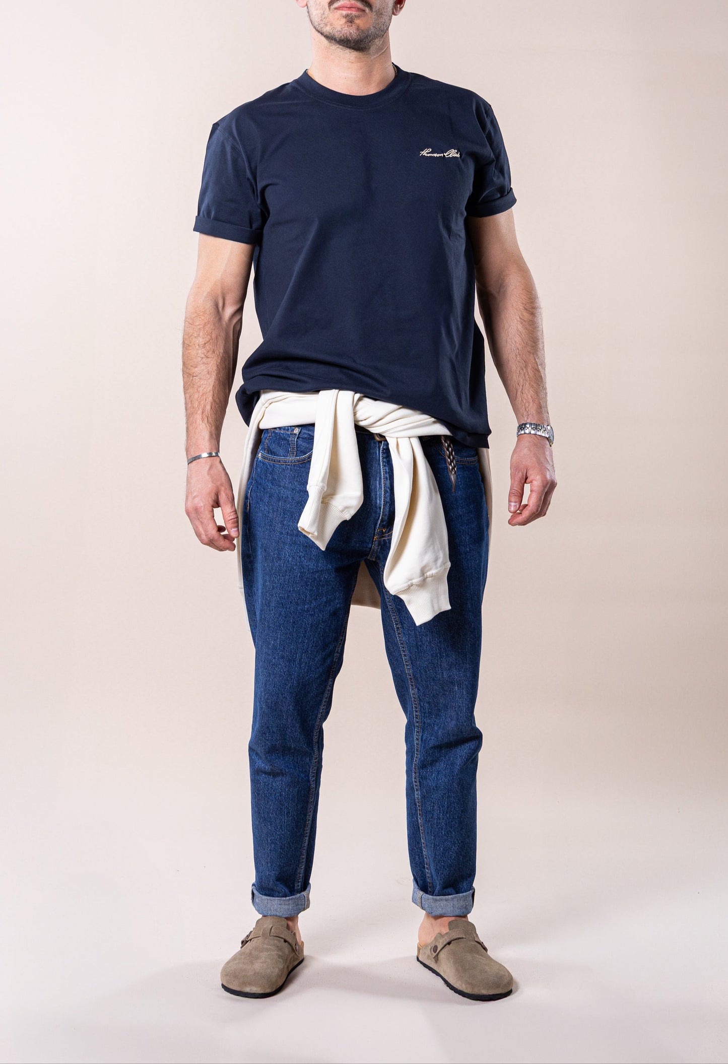 T-shirt de homem azul marinho confecionada em 100% algodão orgânico, jersey de 200g, com corte relaxado. Apresenta gola em rib 1x1, costuras detalhadas, e meia-lua nas costas para conforto extra. Bordado com a assinatura Thomson Club e patch de couro premium não animal, com design em relevo negativo. Peça versátil e intemporal, ideal para diversas ocasiões no dia a dia. Produção sustentável e de alta qualidade.