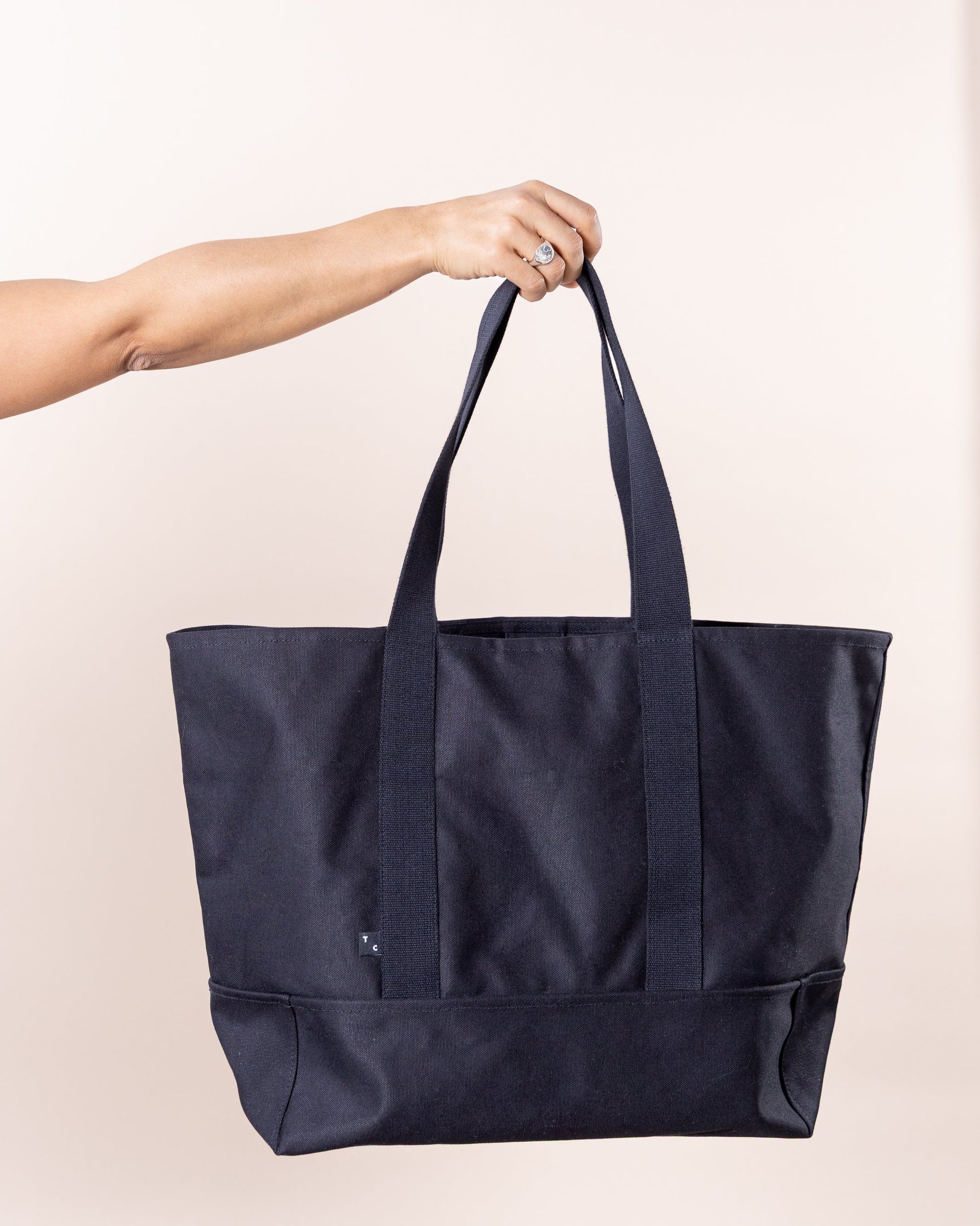 Detalhe das alças reforçadas do saco preto The TC Big Tote em lona resistente
