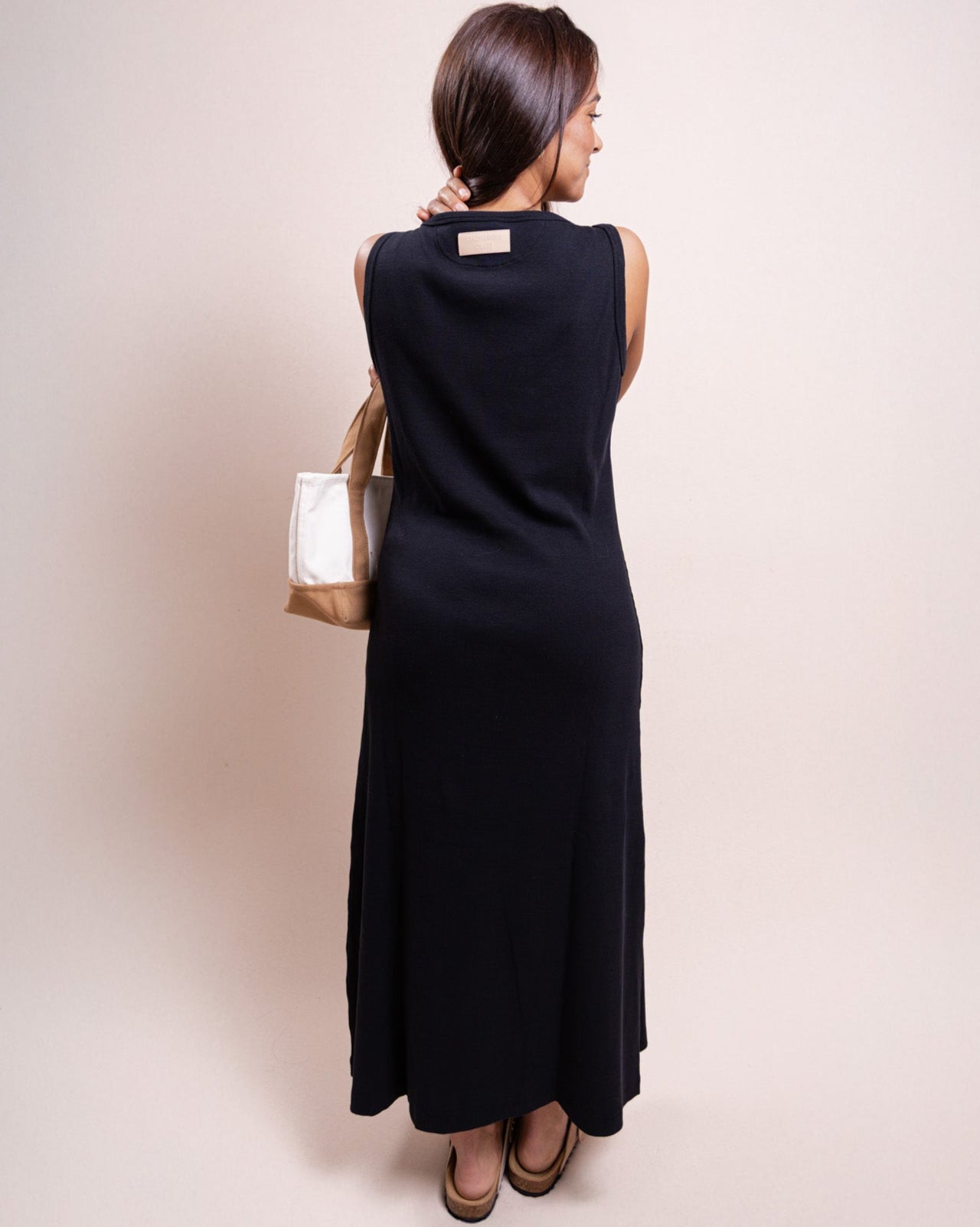Vista lateral do vestido preto The TC Dress Thomson Club em malha rib, corte minimalista
